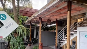 Un espace extérieur abrité, doté d’un escalier, de plantes en pot et d’une enseigne indiquant l’accueil.
