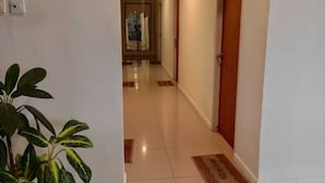 Un couloir d’hôtel avec une plante, un paillasson et une porte.