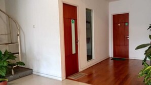 Un couloir avec un plancher en bois, un escalier et deux portes.
