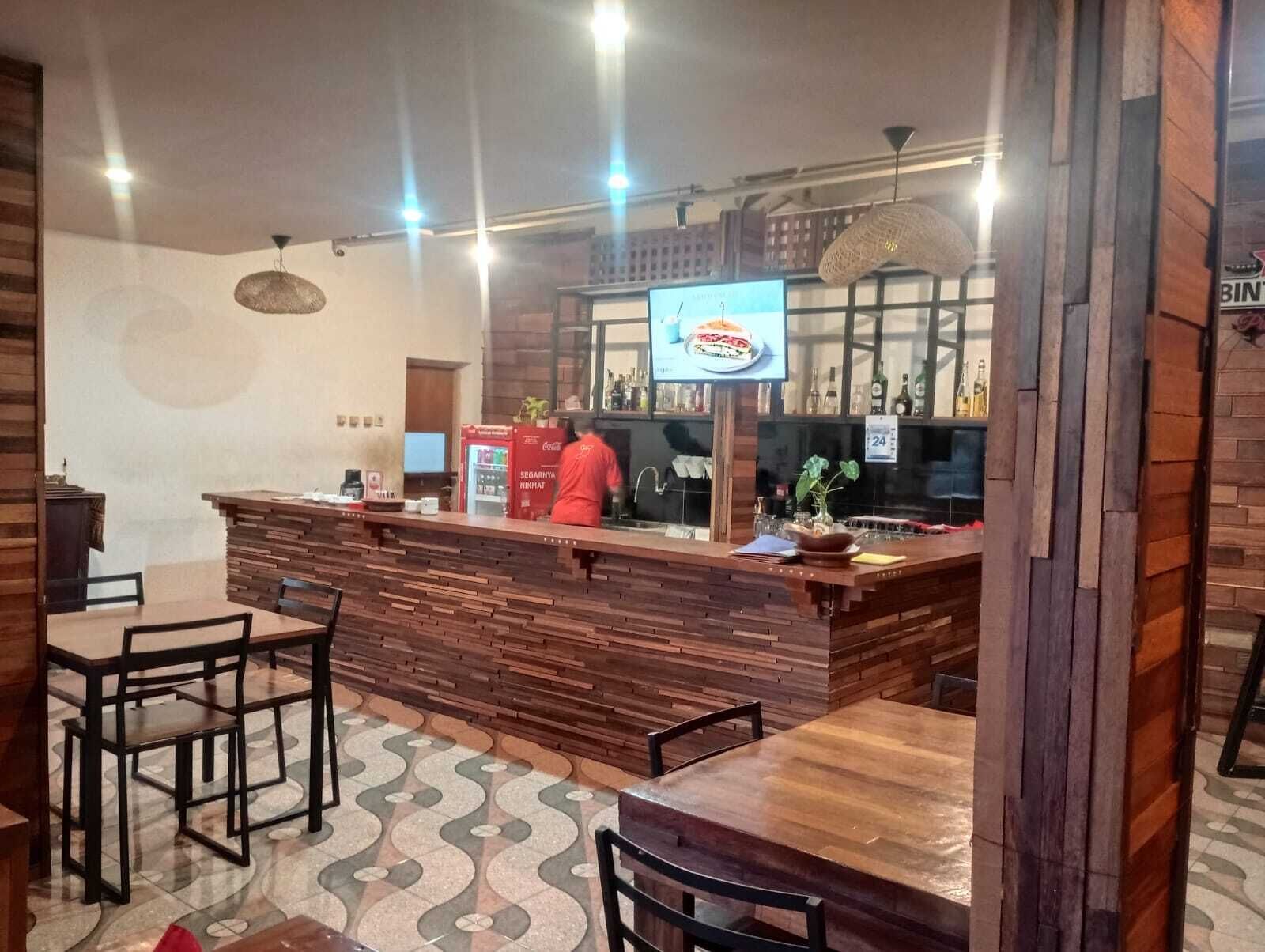 A bar area with a wooden counter, seating, and a television screen.