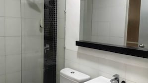 A bathroom with a shower, toilet, sink, and a mirror. - new poppies hotel (Senggigi)
