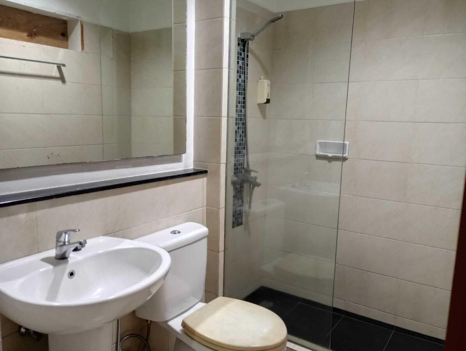 A bathroom with a white sink, toilet, and a glass-enclosed shower area.