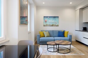 Ein modernes Wohnzimmer mit einer Couch, zwei Couchtischen, einem Fernseher und Kunstwerken an der Wand.