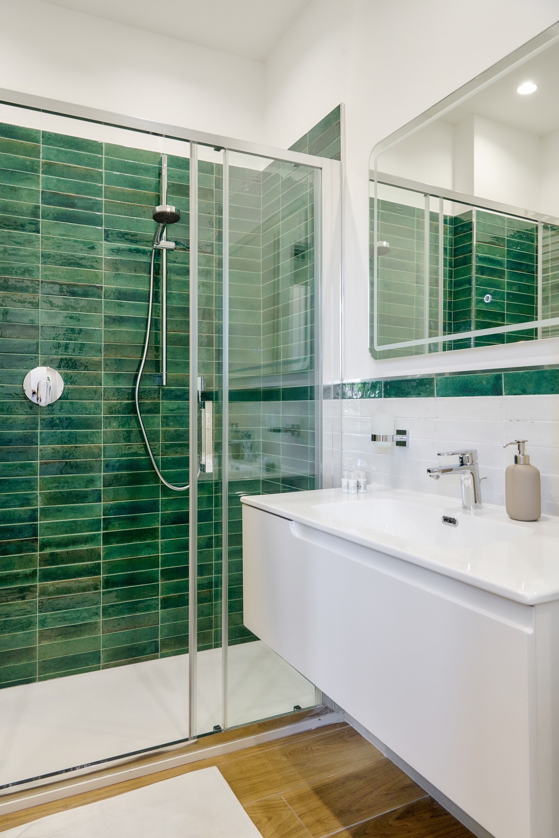 A modern bathroom with a glass shower enclosure, white sink, and a mirror above the vanity.