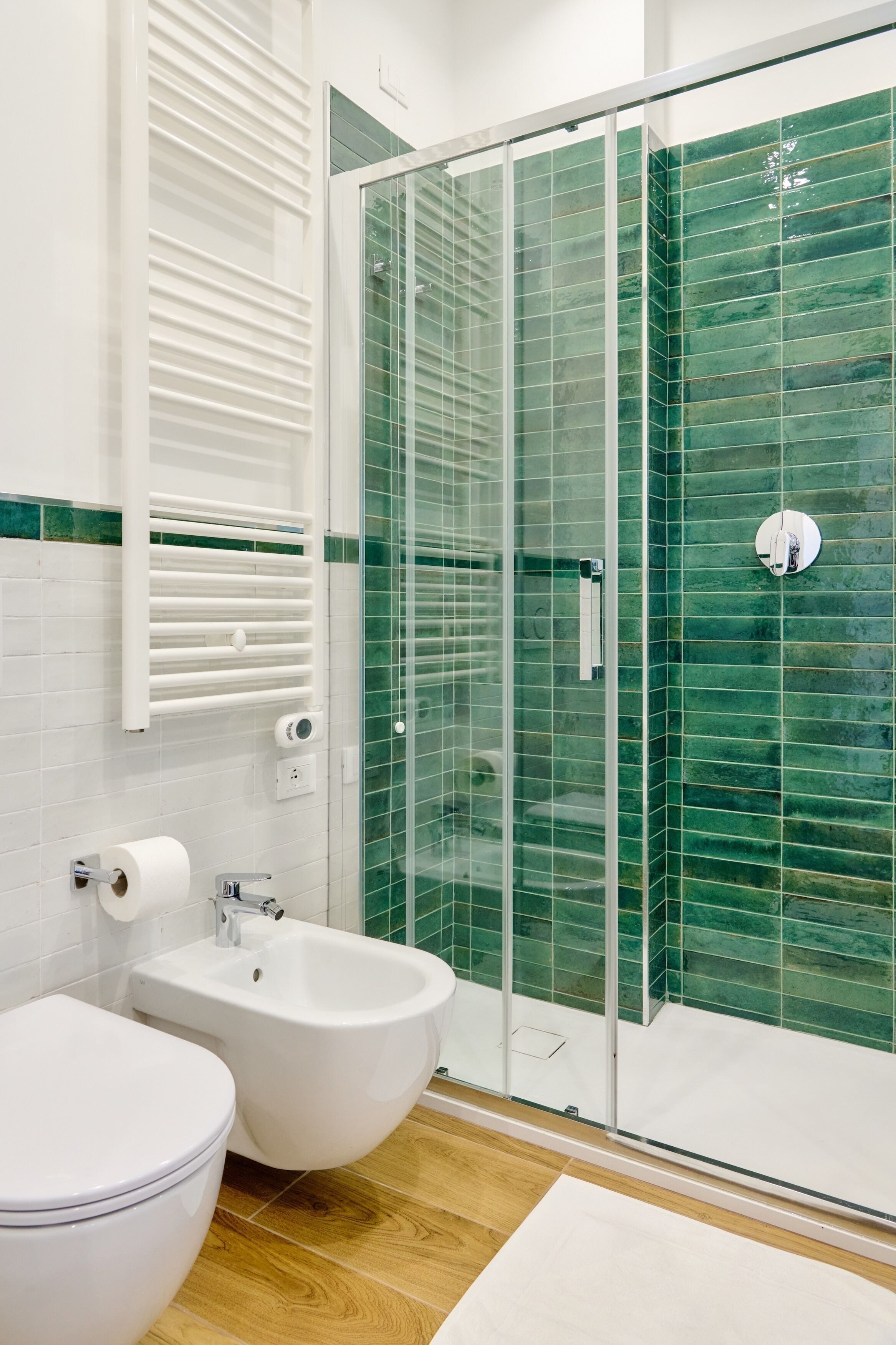 A bathroom with a glass-enclosed shower, a white sink, and a toilet.
