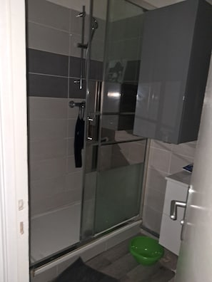 Une salle de bain avec une douche à parois de verre, des toilettes vertes et un lavabo blanc.