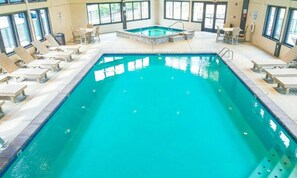 Una piscina interna con poltrone relax e una vasca idromassaggio.