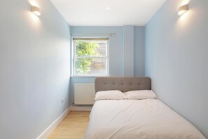 Ein Schlafzimmer mit einem Bett, einem Fenster und einer Heizung.