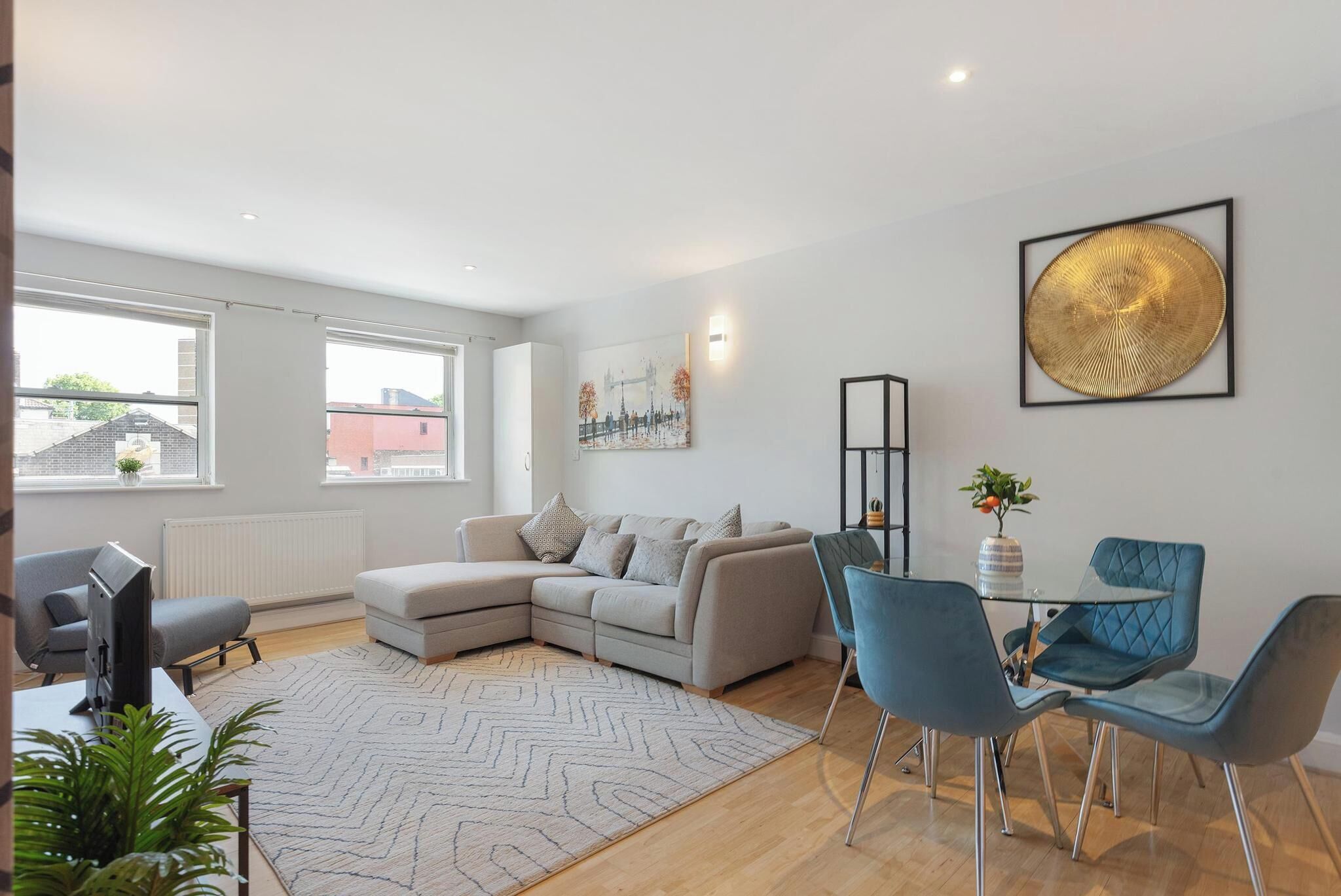 A modern living room with a sofa, chairs, a TV, and artwork on the walls.