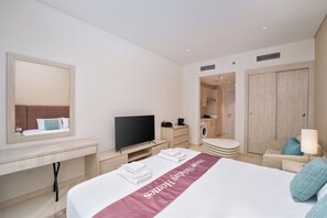 Habitació d'hotel amb llit, televisió, escriptori, mirall, bany i armari.
