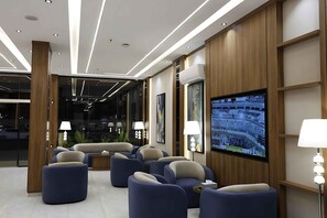 A modern lounge area with sofas and a television screen displaying an event.