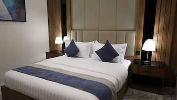 A hotel room with a large bed, two bedside tables, a headboard, and a painting on the wall.
