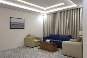 A modern hotel room with a sofa, armchairs, a coffee table, and a painting on the wall. - RADIX MILLENNIUM (Al-Rawna District)