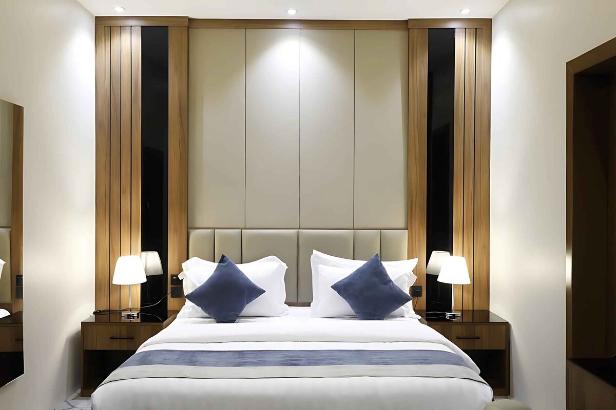 A hotel room with a large bed, two bedside tables with lamps, and a wooden headboard.