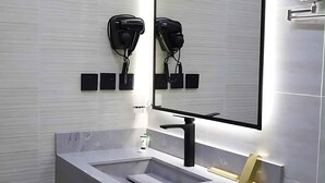 A modern bathroom with a white sink, a black faucet, and a large mirror. - RADIX MILLENNIUM (Al-Rawna District)