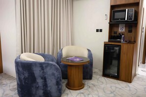 A hotel room with two armchairs, a small table, a microwave, and a coffee machine. - RADIX MILLENNIUM (Al-Rawna District)