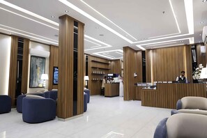 A modern hotel lobby with a reception desk, seating area, and a large artwork on the wall. - RADIX MILLENNIUM (Al-Rawna District)