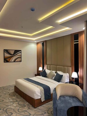 A modern hotel room with a large bed, bedside lamps, a headboard, and a ceiling light fixture.