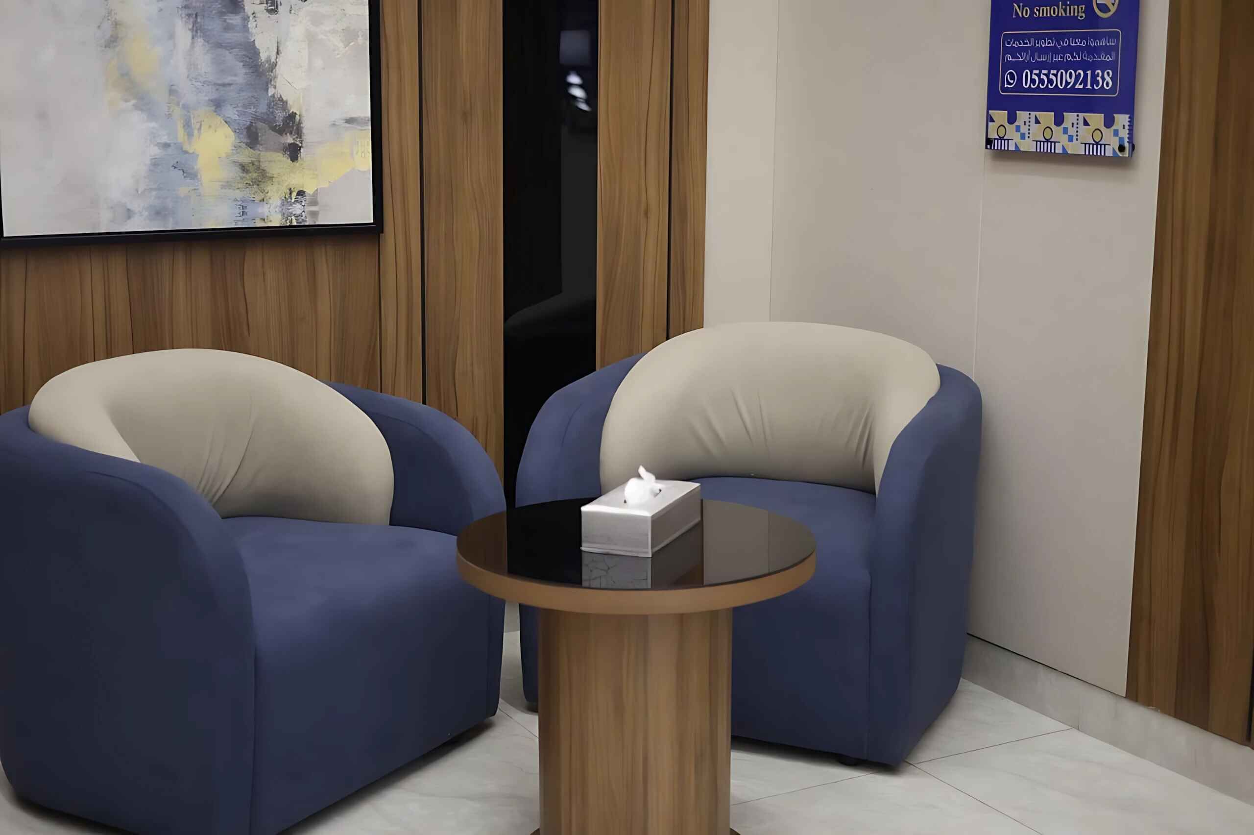 Una habitación con dos sillones azules y una pequeña mesa redonda con una caja de pañuelos.