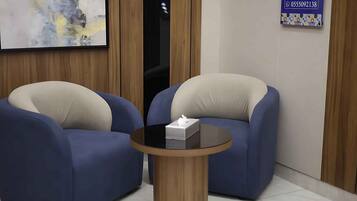 Una habitación con dos sillones azules y una pequeña mesa redonda con una caja de pañuelos.