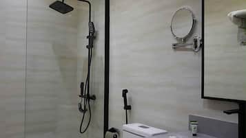 Un baño moderno con ducha de vidrio, lavamanos blanco y un espejo grande.