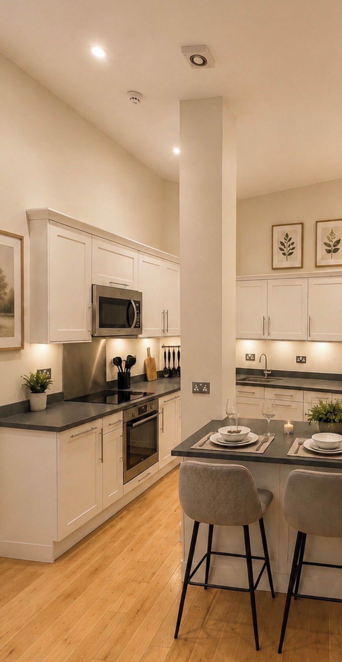 Een moderne keuken met witte kasten, een centraal eiland met barkrukken, en een magnetron boven de oven.