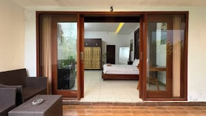 A room with a bed, a sofa, and a sliding glass door leading to an outdoor area. - Pondok Cintya Kerobokan Canggu (Badung)