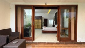 A room with a bed, a sofa, and a sliding glass door leading to an outdoor area. - Pondok Cintya Kerobokan Canggu (Badung)