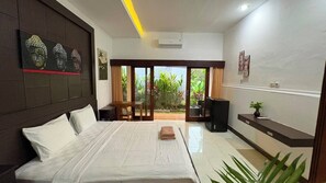 A hotel room with a bed, a desk, a chair, a television, and a view of the outdoors. - Pondok Cintya Kerobokan Canggu (Badung)