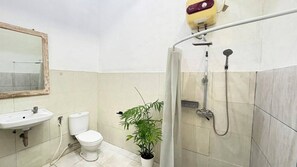 A bathroom with a sink, toilet, shower, and a potted plant. - Pondok Cintya Kerobokan Canggu (Badung)