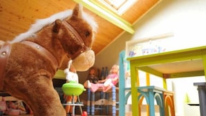 Ein Zimmer mit Holzboden, einem grünen Tisch und einem Stuhl.