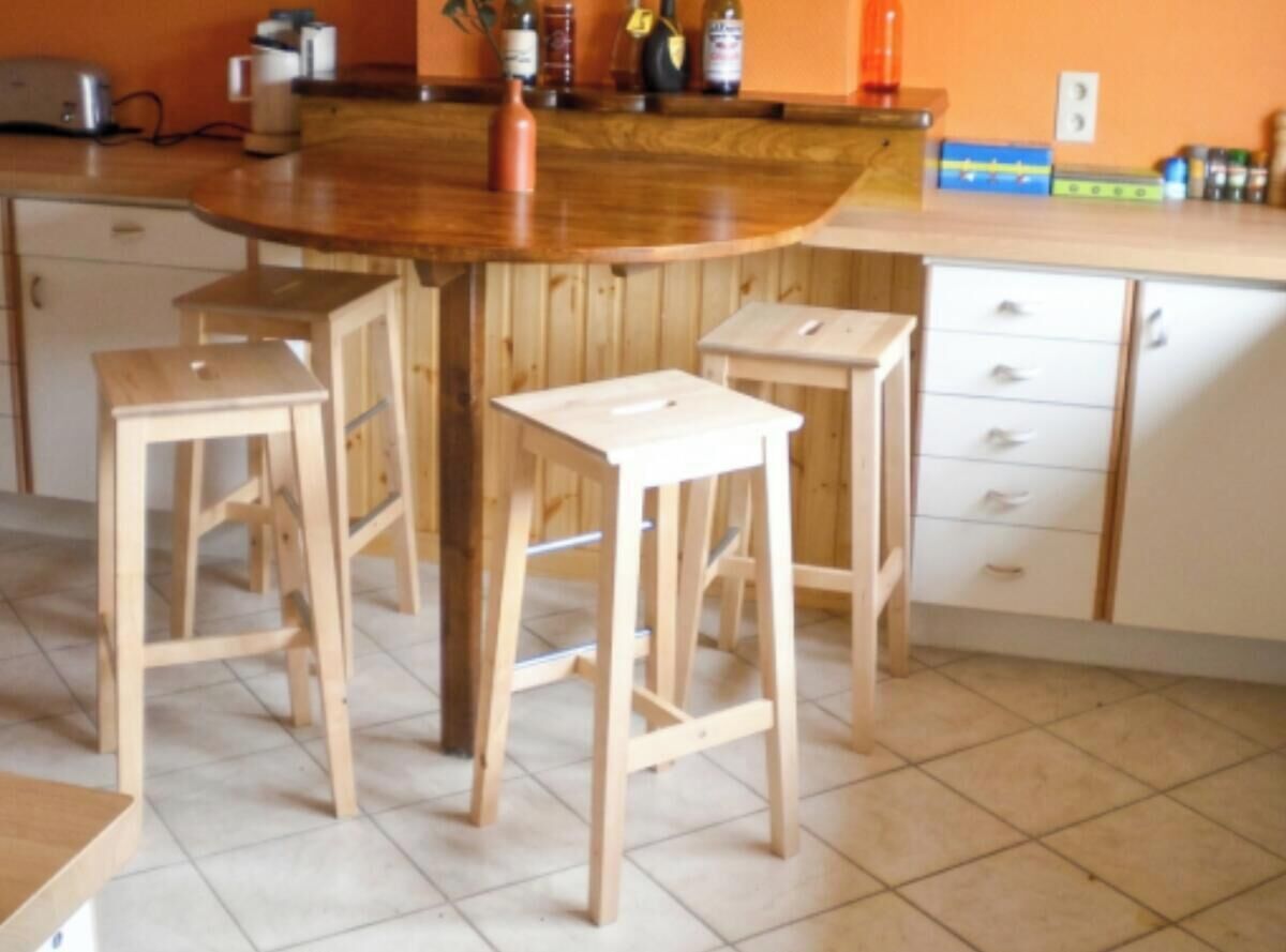 Una cocina con una isla de madera, taburetes y armarios.