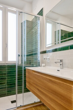 A modern bathroom with a glass shower enclosure, a wooden vanity, and green-tiled walls. - Casa e Appartamento Vacanze Gallese 8 (Roma)