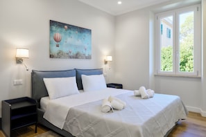 A hotel room with a bed, two bedside tables, a painting, and a window with a view. - Casa e Appartamento Vacanze Gallese 8 (Roma)