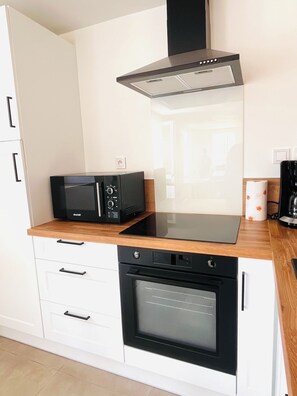 A modern kitchen with a built-in oven, microwave, and a range hood. - Our traditional house with a courtyard, 3 km from the sea   (Carneville)