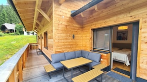 A wooden cabin with a covered porch, a sofa, and a table. - Chalet Rehblick (Bad Kleinkirchheim)