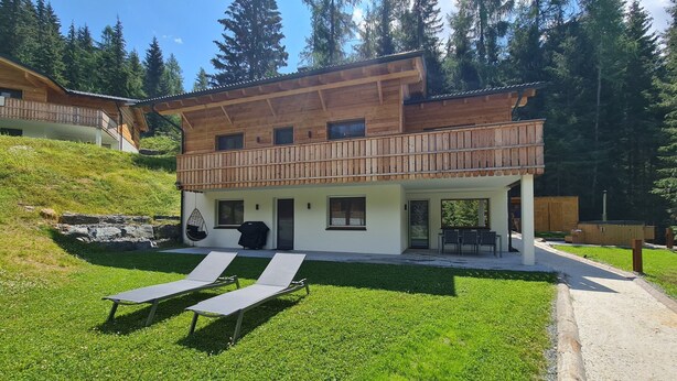 A modern wooden chalet with a balcony, outdoor seating, and a grassy yard. - Chalet Rehblick (Bad Kleinkirchheim)