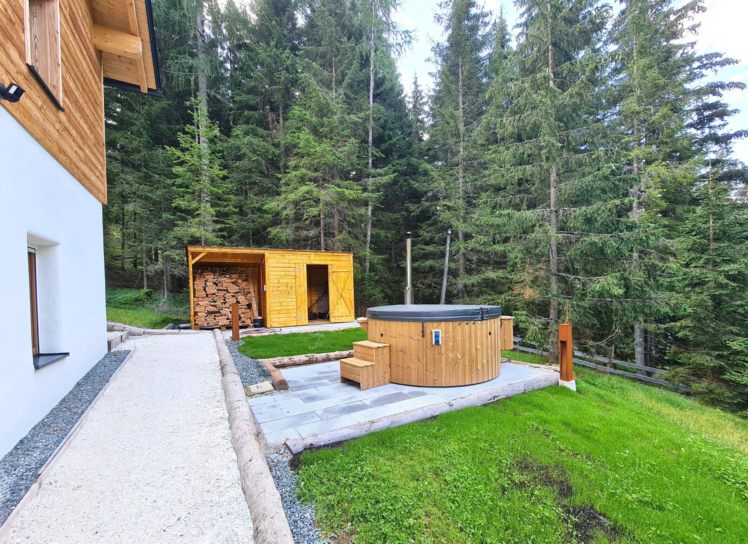 A modern wooden cabin with a sauna and a stack of firewood.