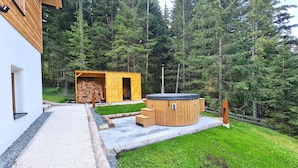 A modern wooden cabin with a sauna and a stack of firewood. - Chalet Rehblick (Bad Kleinkirchheim)