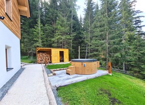 A modern wooden cabin with a sauna and a stack of firewood. - Chalet Rehblick (Bad Kleinkirchheim)