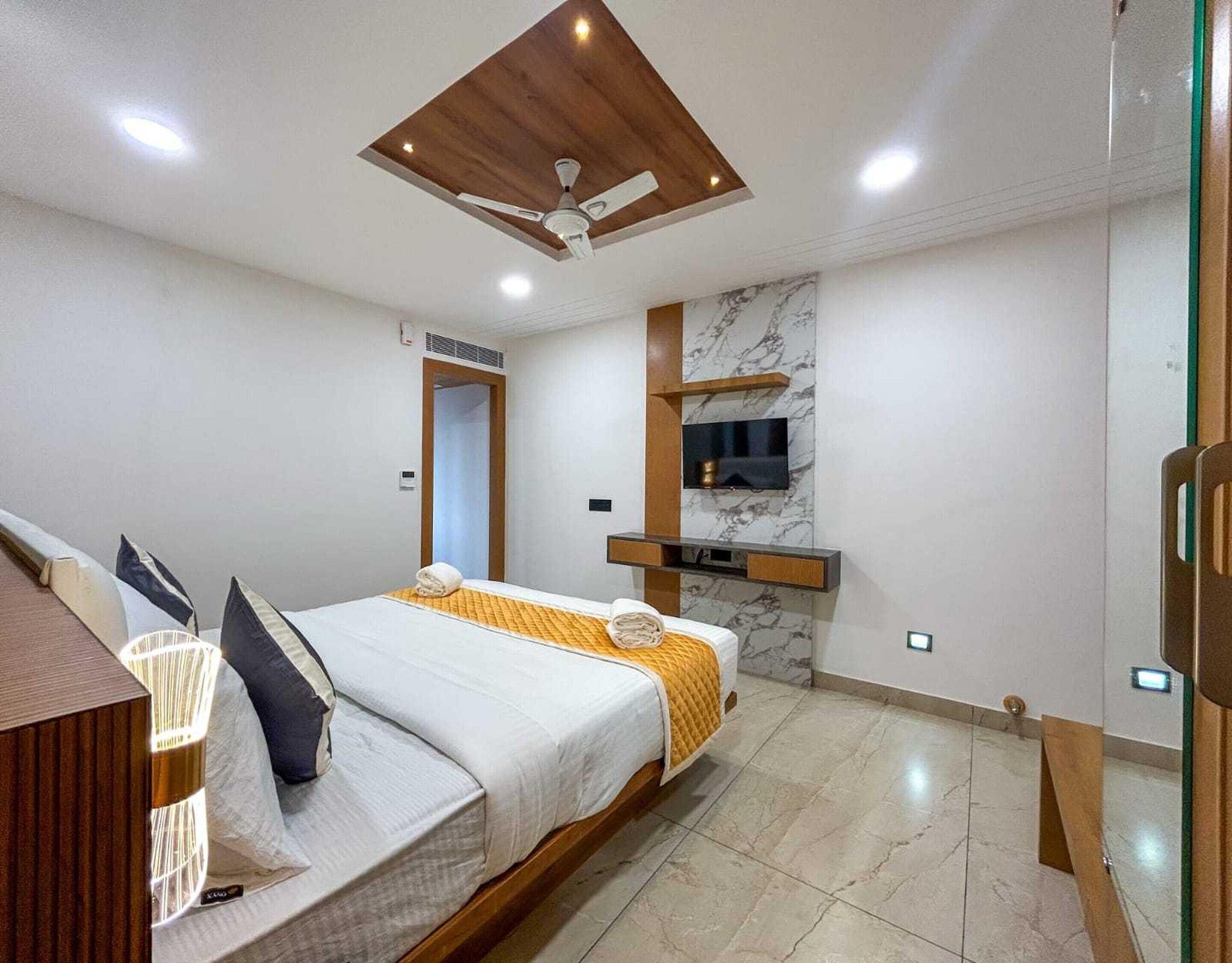 Een hotelkamer met een bed, een aan de muur bevestigde televisie en een plafondventilator.
