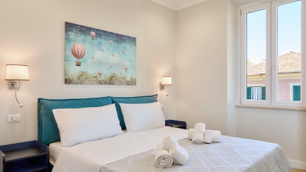 Une chambre d’hôtel avec un lit, deux tables de chevet, un tableau et une fenêtre.