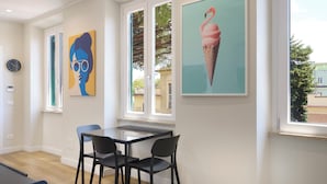 Une pièce comprenant une table à manger, deux chaises, une horloge et des œuvres d’art accrochées aux murs.