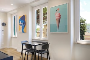 Una habitación con una mesa de comedor, dos sillas, un reloj y obras de arte en las paredes.