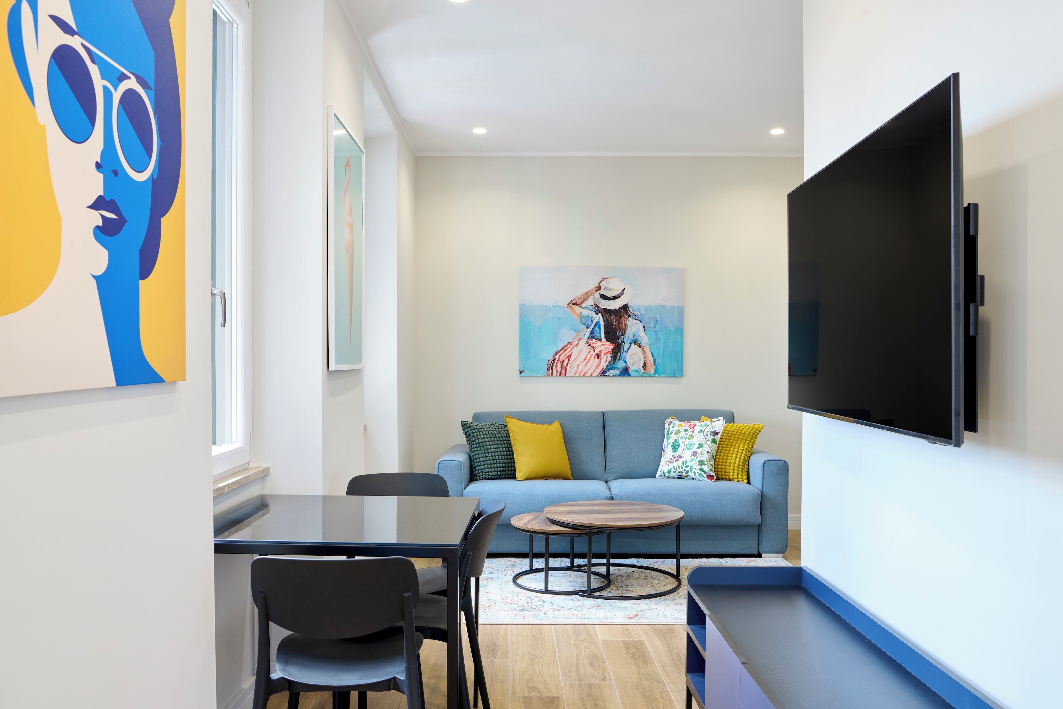 A modern living room with a sofa, a coffee table, a TV, and artwork on the walls.