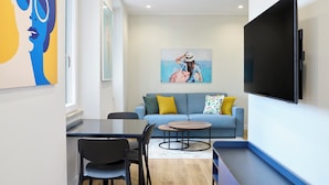 Un salon moderne avec un canapé, une table basse, un téléviseur et des œuvres d’art accrochées aux murs.