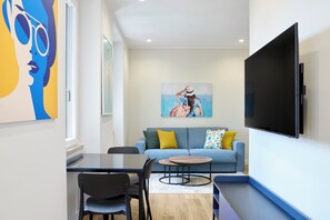 Una sala de estar moderna con un sofá, una mesa de centro, un televisor y obras de arte en las paredes.