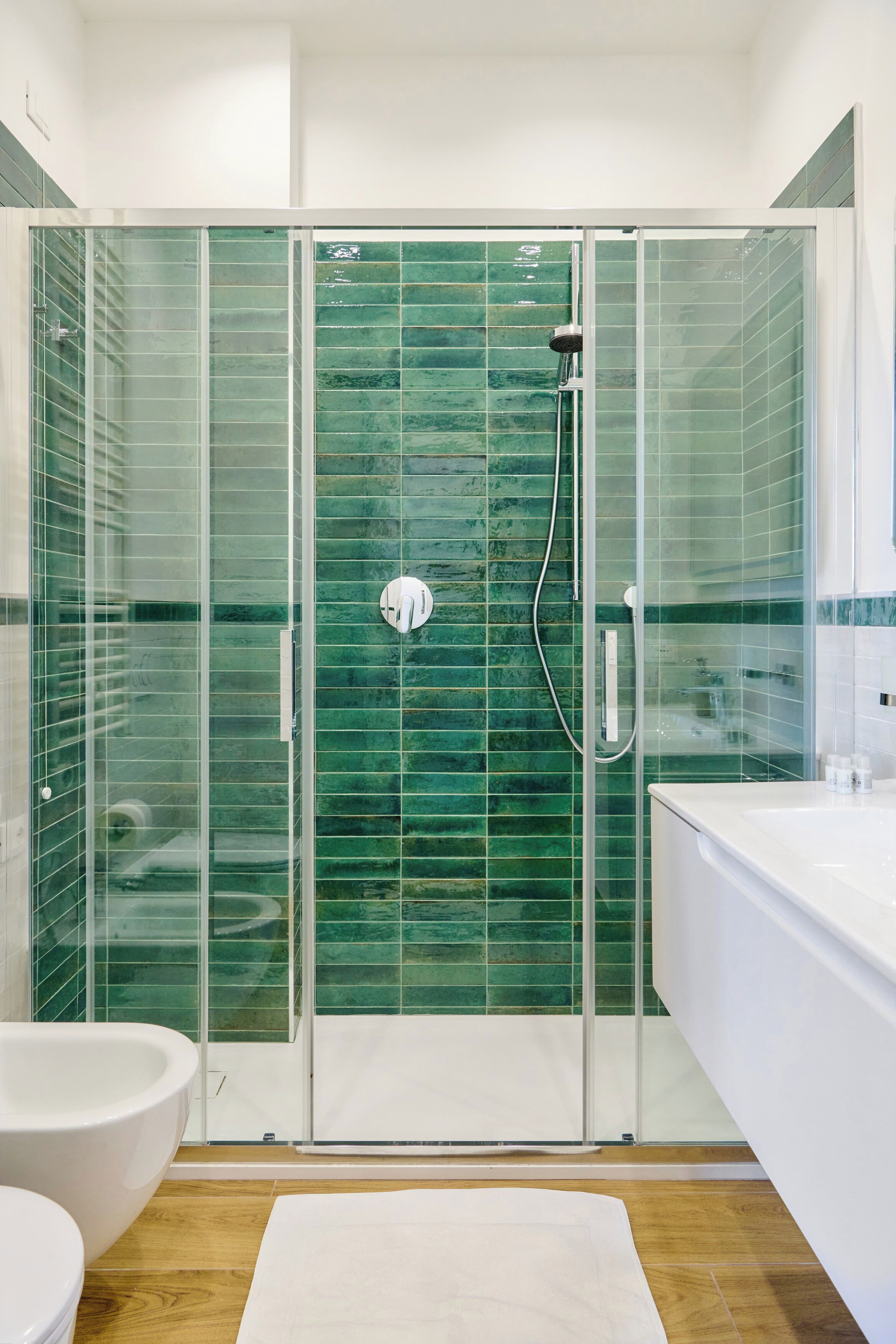 A modern bathroom with a glass-enclosed shower, a white bathtub, and a white sink.