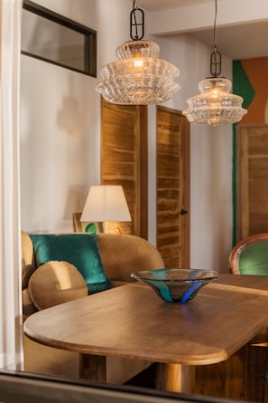 Un área de comedor con una mesa de madera, un centro de mesa con un cuenco de vidrio y una araña.
