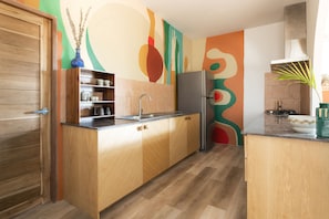 Una cocina moderna con armarios de madera, un refrigerador de acero inoxidable y un llamativo mural abstracto.